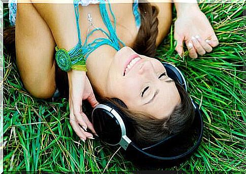 Smiling woman lying on the grass listening to music