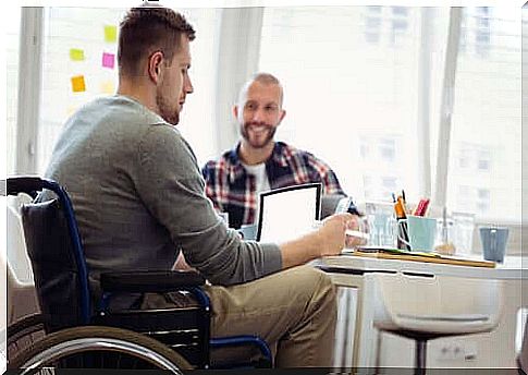 A man in a wheelchair sitting at a table working on his laptop.