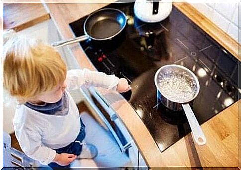 A child touching a hob with hot pots on.