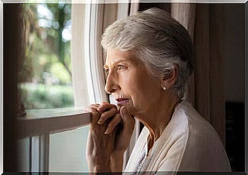 An elderly woman looking out the window.