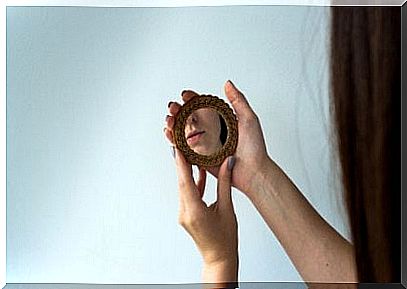 A woman looking into a hand mirror.