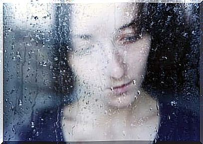 A sad woman behind a window.